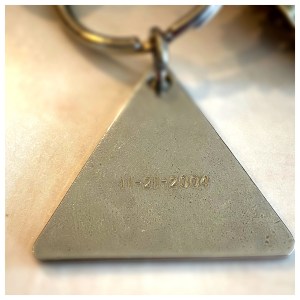 Side of a triangular keychain engraved with the date 11/21/2004